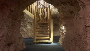Een gewelfde stenen tunnel die uitkomt bij een houten trap.