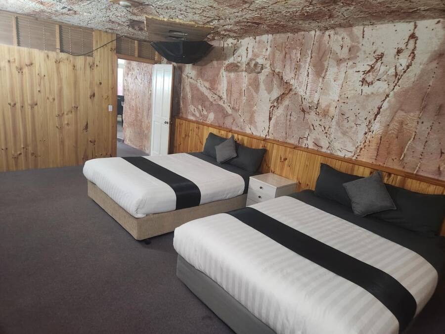 Una stanza con due letti, ognuno dotato di una testiera in legno e un comodino.