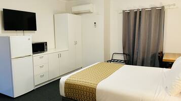 A hotel room with a bed, a TV, a microwave, and a wardrobe.