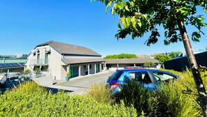 A modern building with a flat roof, a balcony, and a car parked in front. - The Menzies Ballarat (Bakery Hill)