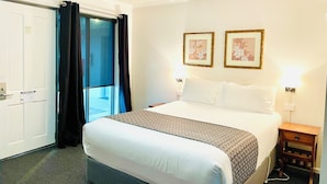 A hotel room with a bed, a nightstand, two framed pictures on the wall, a door with a sign, and a window with curtains. - The Menzies Ballarat (Bakery Hill)