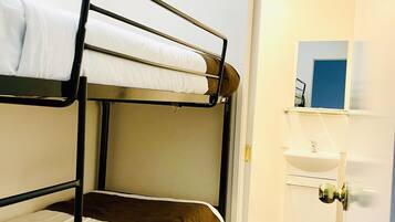 A bunk bed room with a bathroom visible through an open door.