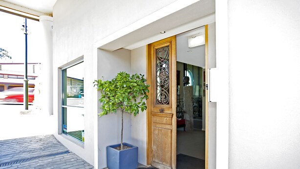 A modern entrance with a potted tree, a wooden door, and a clear view of the street outside. - The Menzies Ballarat (Bakery Hill)