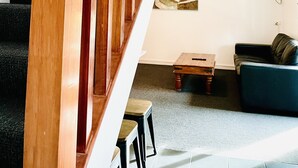 A wooden staircase with a handrail leading to a second floor. There is a small table and a blue sofa on the lower level. - The Menzies Ballarat (Bakery Hill)