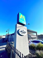 Un letrero de hotel con un logotipo destacado y el nombre 'The Menzies Hotel' sobre un cielo azul despejado.