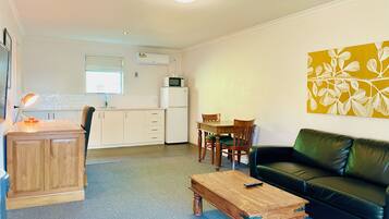 A compact living space with a kitchenette, a dining area, and a seating area with a couch and coffee table.