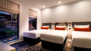 Habitación de hotel con dos camas, un ventanal con vistas a la ciudad y un diseño moderno con un papel tapiz decorativo.