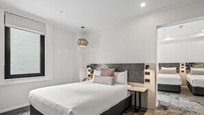 A modern hotel room with a large bed, bedside tables, a unique wall art, and a patterned carpet. - Batman’s Hill on Collins (Melbourne)