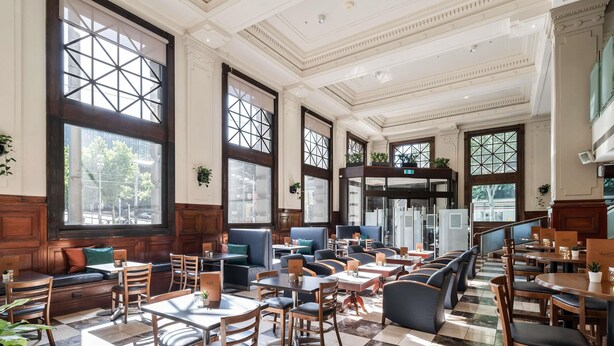 A spacious restaurant with high ceilings, large windows, and a mix of seating options including booths and tables. - Batman’s Hill on Collins (Melbourne)