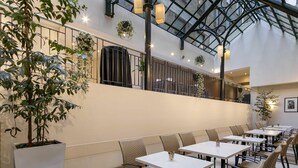 A spacious indoor dining area with high ceilings, modern furniture, and decorative plants. - Batman’s Hill on Collins (Melbourne)