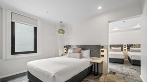Una habitación de hotel moderna con una cama grande, mesitas de noche, una ventana con persianas y una alfombra estampada.