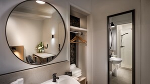 Un baño moderno con un espejo redondo, un lavamanos y una ducha.