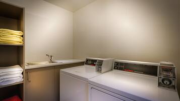 A laundry area with a washing machine, dryer, and a shelf with folded towels.