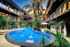 Una piscina al aire libre, sombrillas, sillones reclinables de piscina
