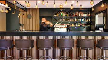 Un bar con taburetes, un camarero y estantes llenos de botellas de licores.