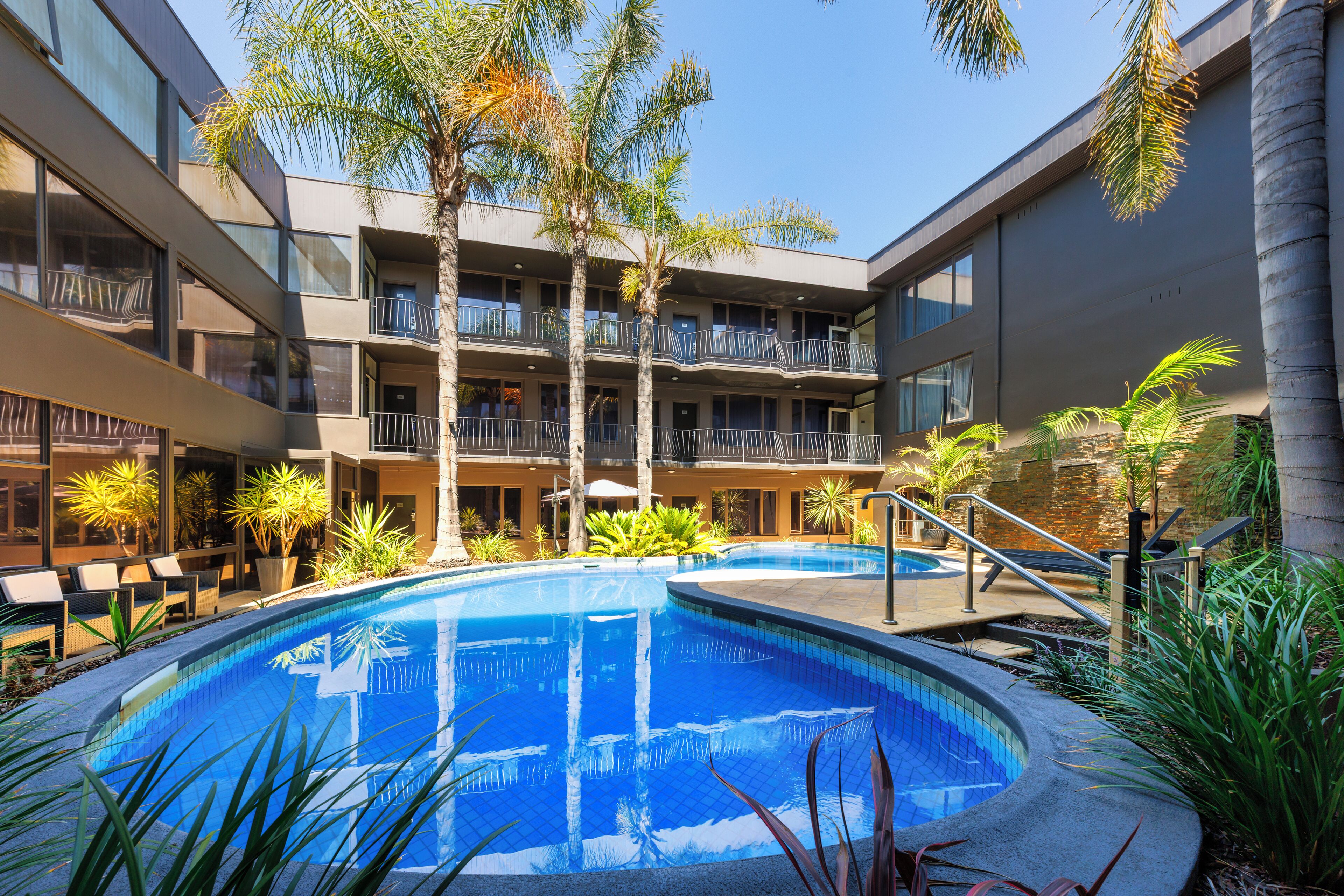 Un hotel con piscina, balcones y palmeras.