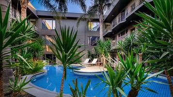 Una piscina al aire libre, sombrillas, tumbonas