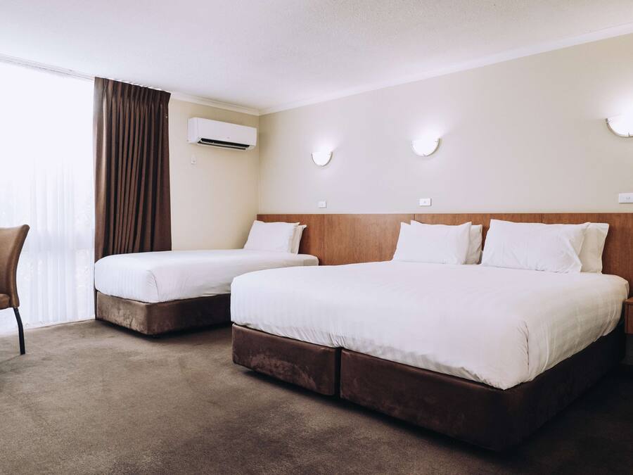 A hotel room with two beds, a chair, and a nightstand.