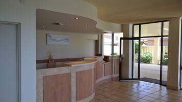 A reception area with a curved counter, a framed artwork above it, and a glass door leading outside.