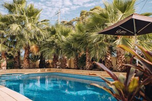 Una piscina al aire libre, sombrillas, sillones reclinables de piscina