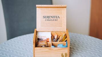 A wooden box labeled "SERENITEA A Work of Art" containing various items.