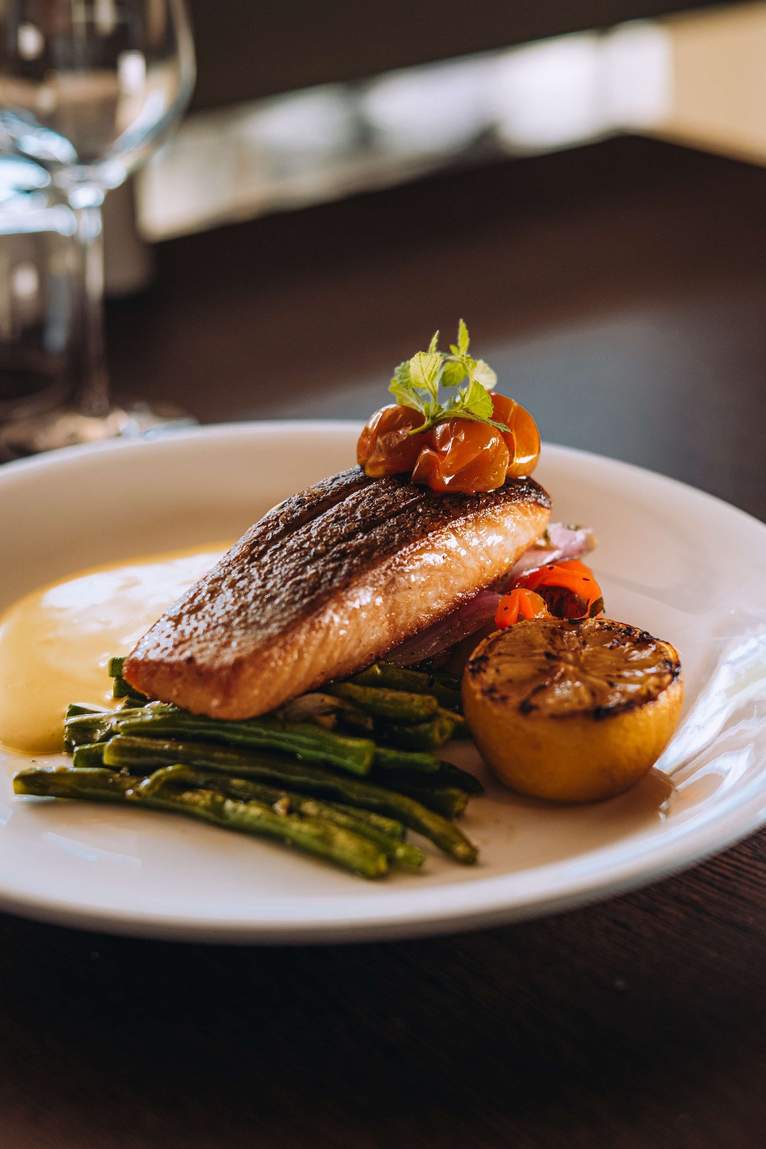 A plate of food with a piece of fish, asparagus, and a grilled vegetable.