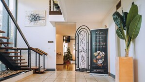 Un hall d’hôtel moderne avec un escalier, un sapin de Noël, une plante décorative et un espace d’accueil.