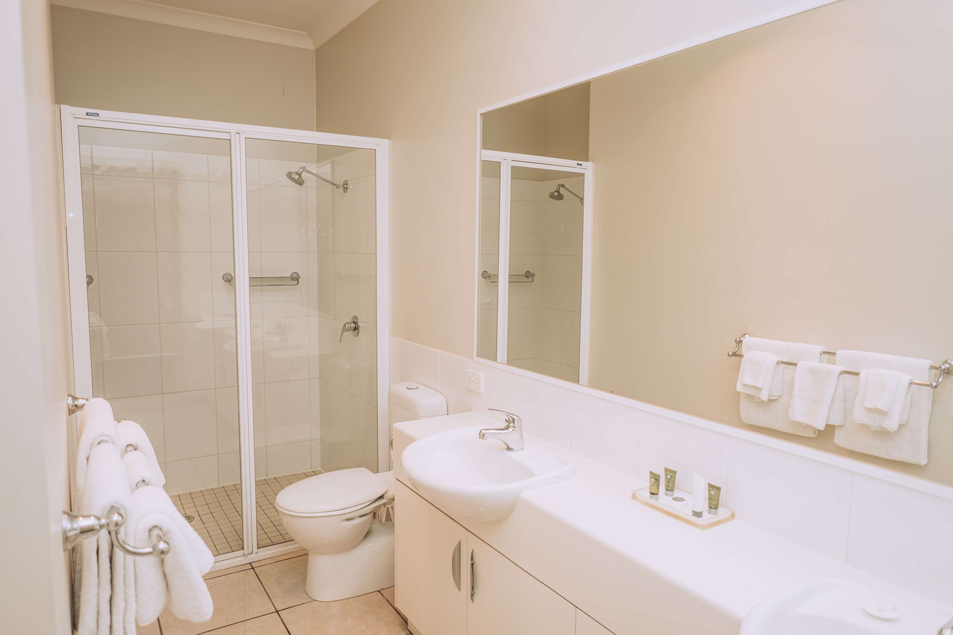 A bathroom with a glass-enclosed shower, a white sink, and a toilet.
