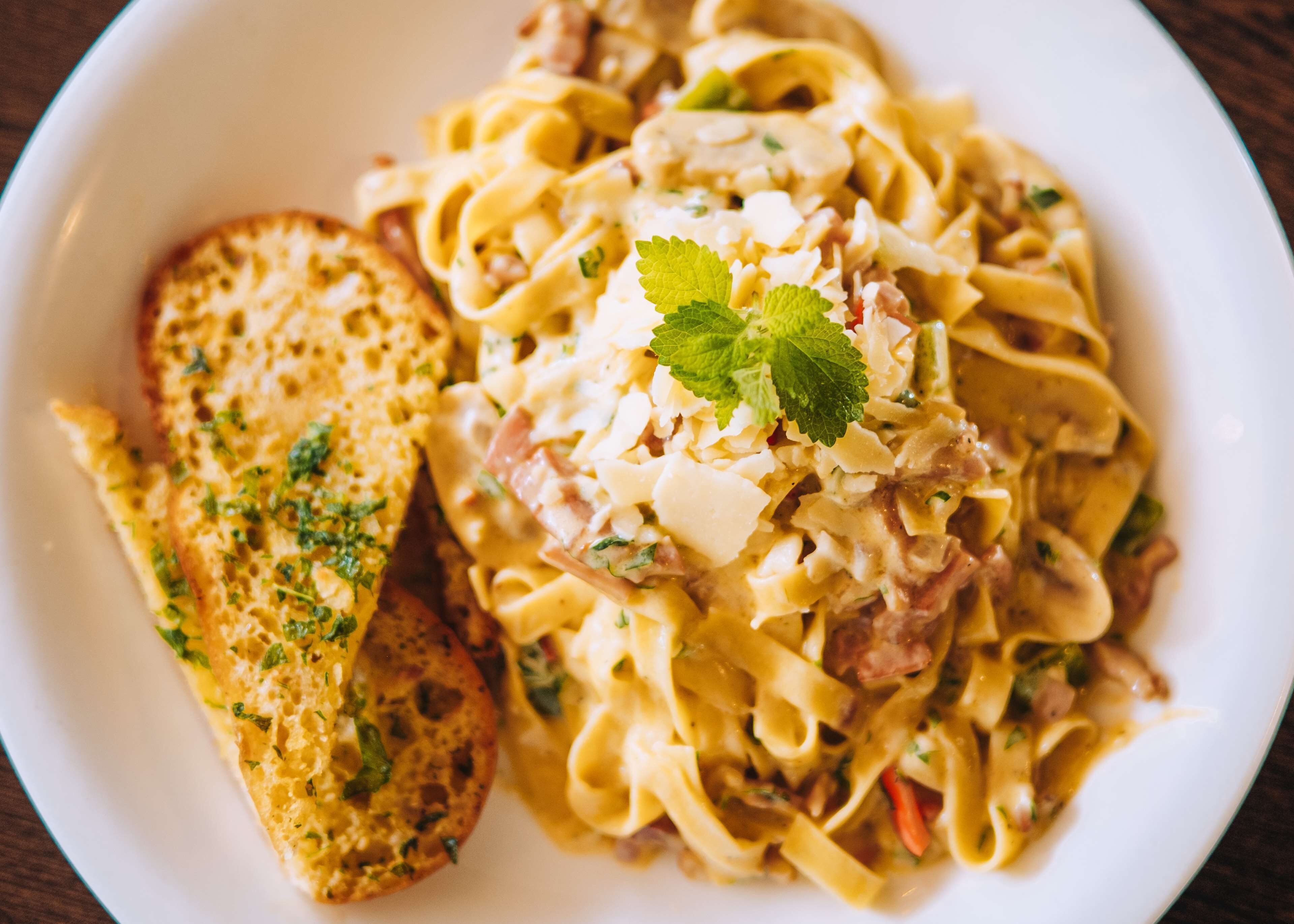 A plate of pasta with a garnish of herbs and a piece of bread.