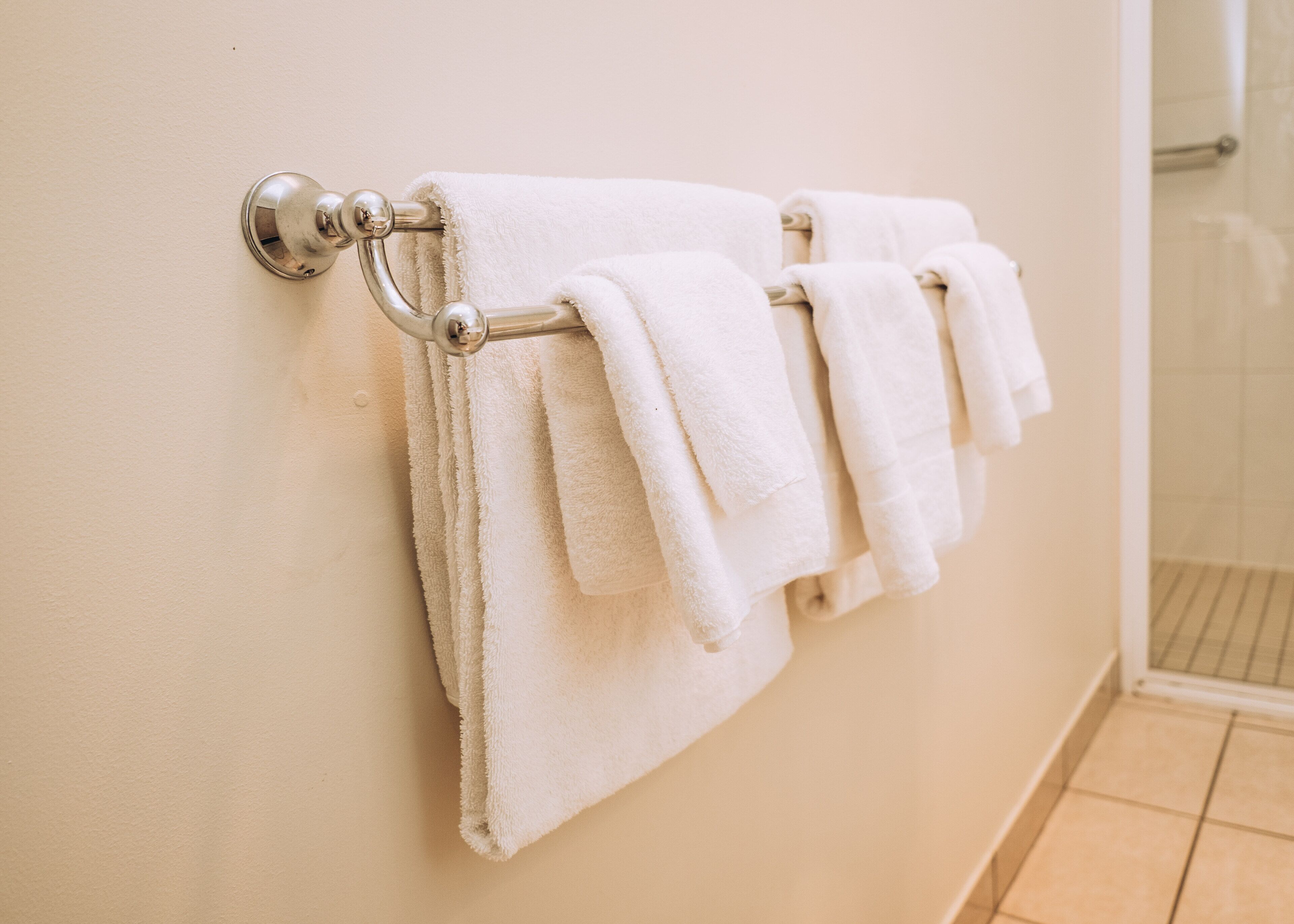 Un baño con un perchero que sostiene varias toallas blancas.