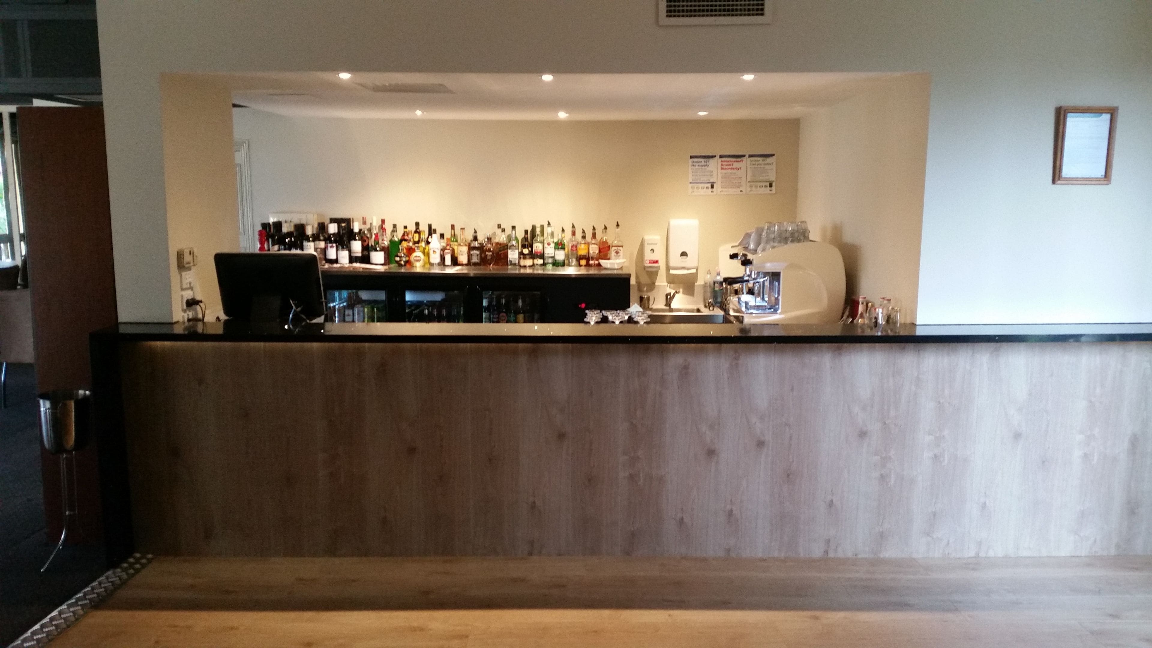 A bar area with a wooden counter, various bottles, and a coffee machine.