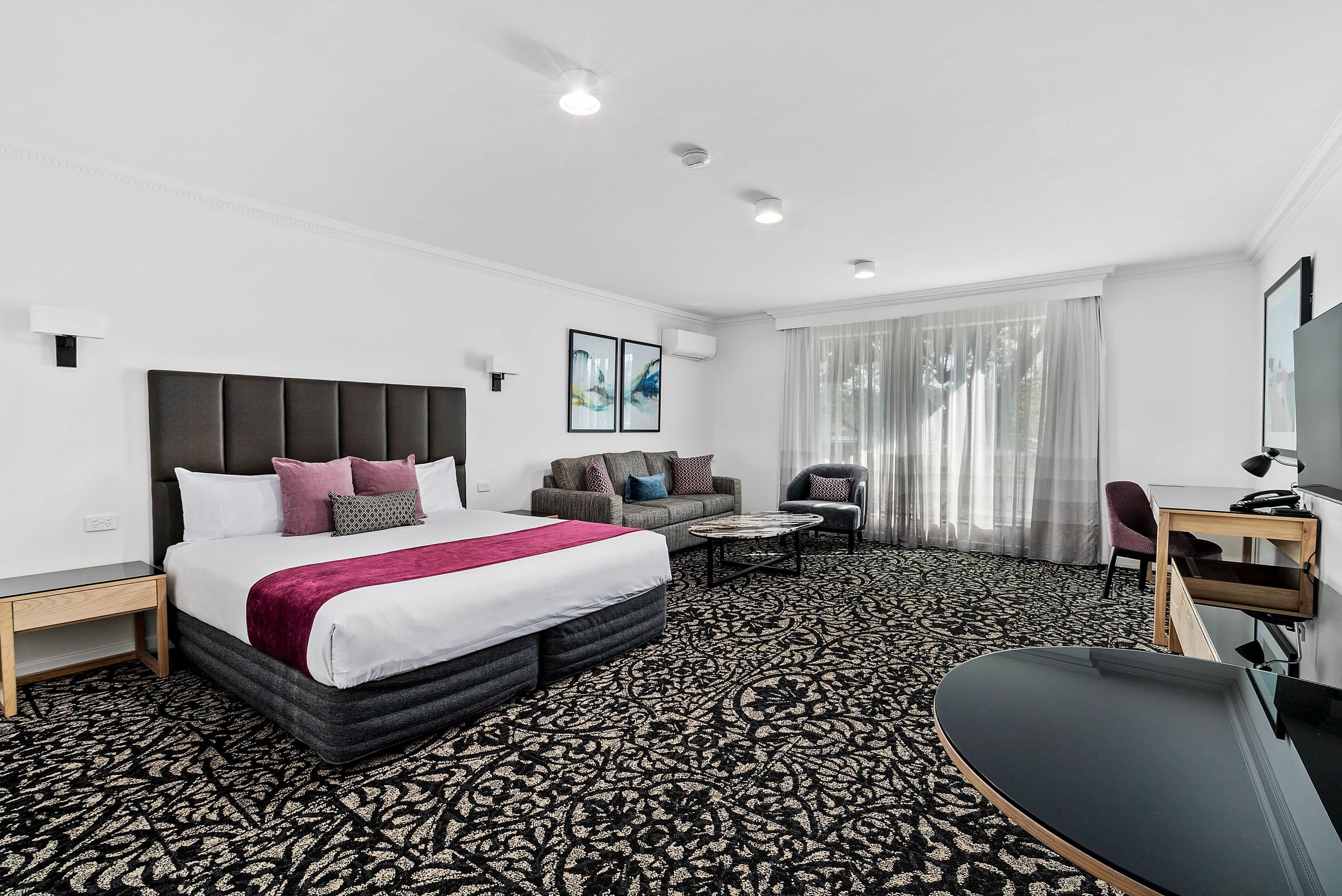 Een hotelkamer met een bed, een slaapbank, een bureau en een stoel.