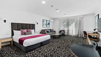 Een hotelkamer met een bed, een slaapbank, een bureau en een stoel.