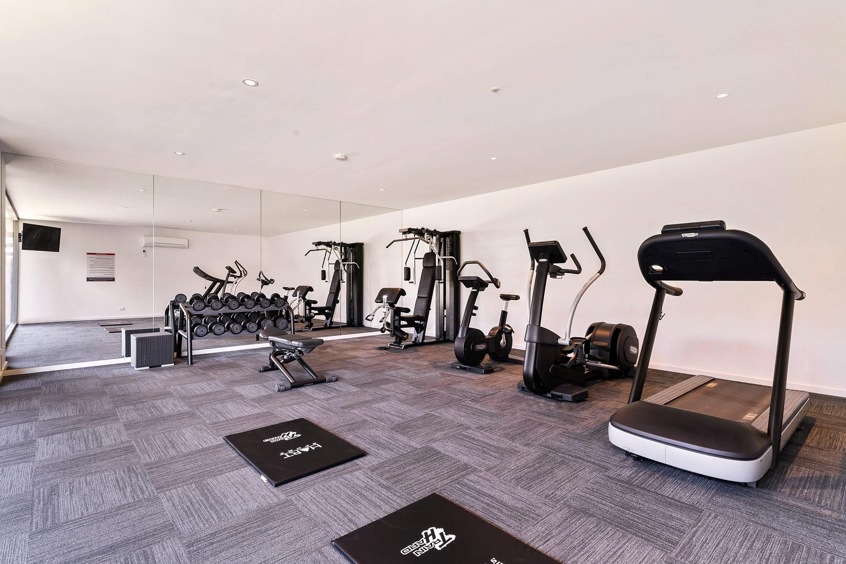 A modern gym with various exercise equipment, including treadmills, elliptical machines, and free weights.