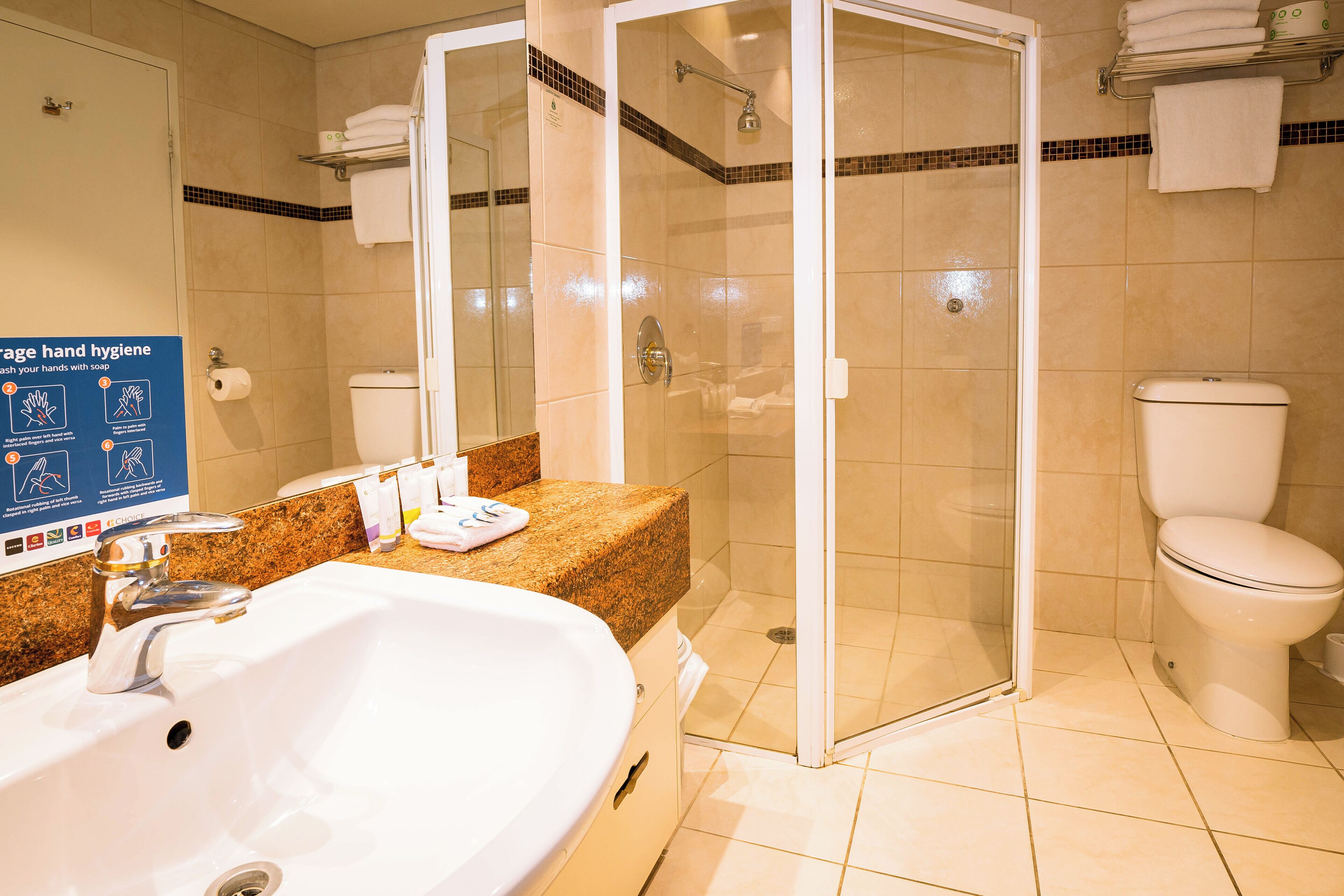 A bathroom with a white sink, a glass-enclosed shower, and a toilet.