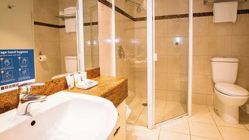 A bathroom with a white sink, a glass-enclosed shower, and a toilet.