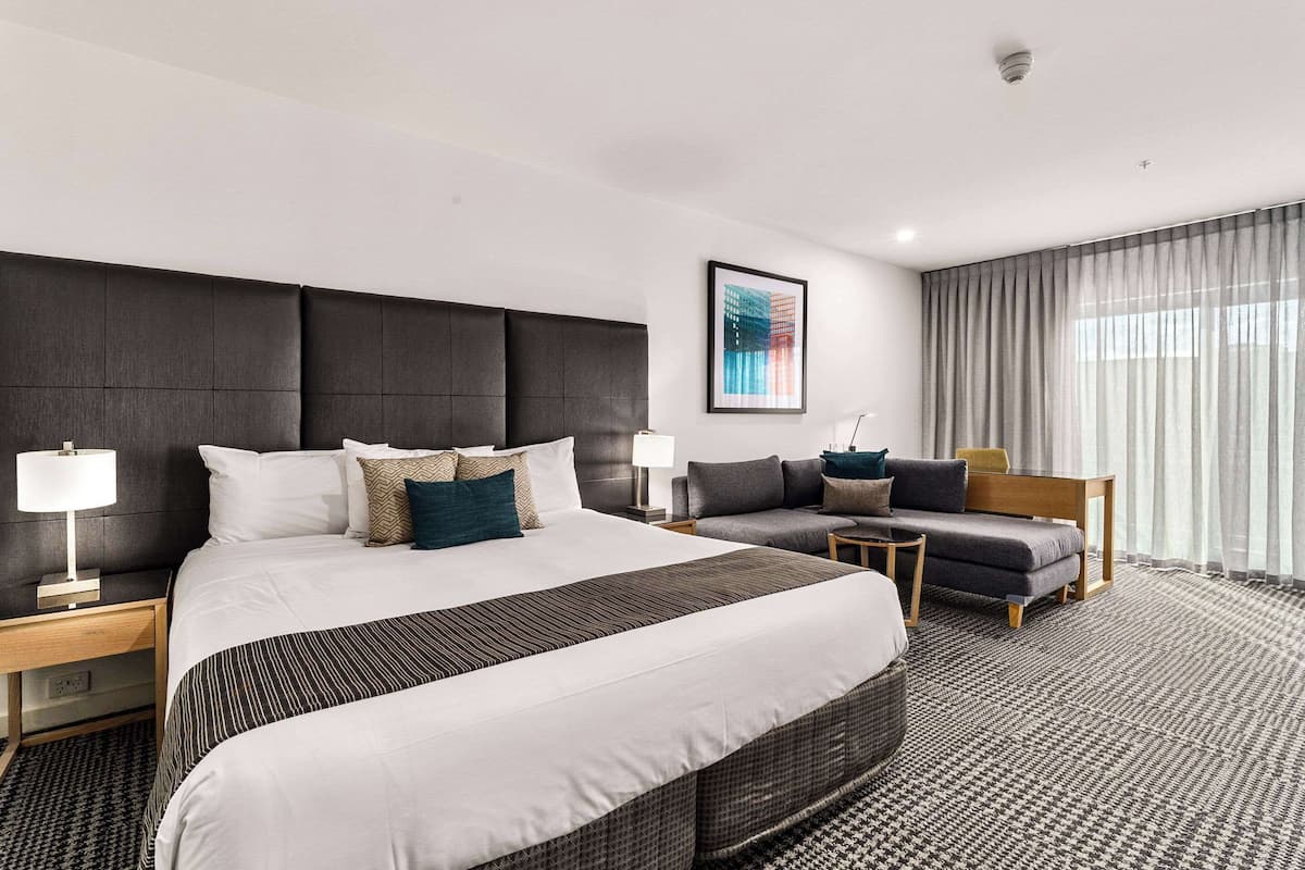Una habitación de hotel moderna con una cama grande, un sofá, un escritorio y una silla.