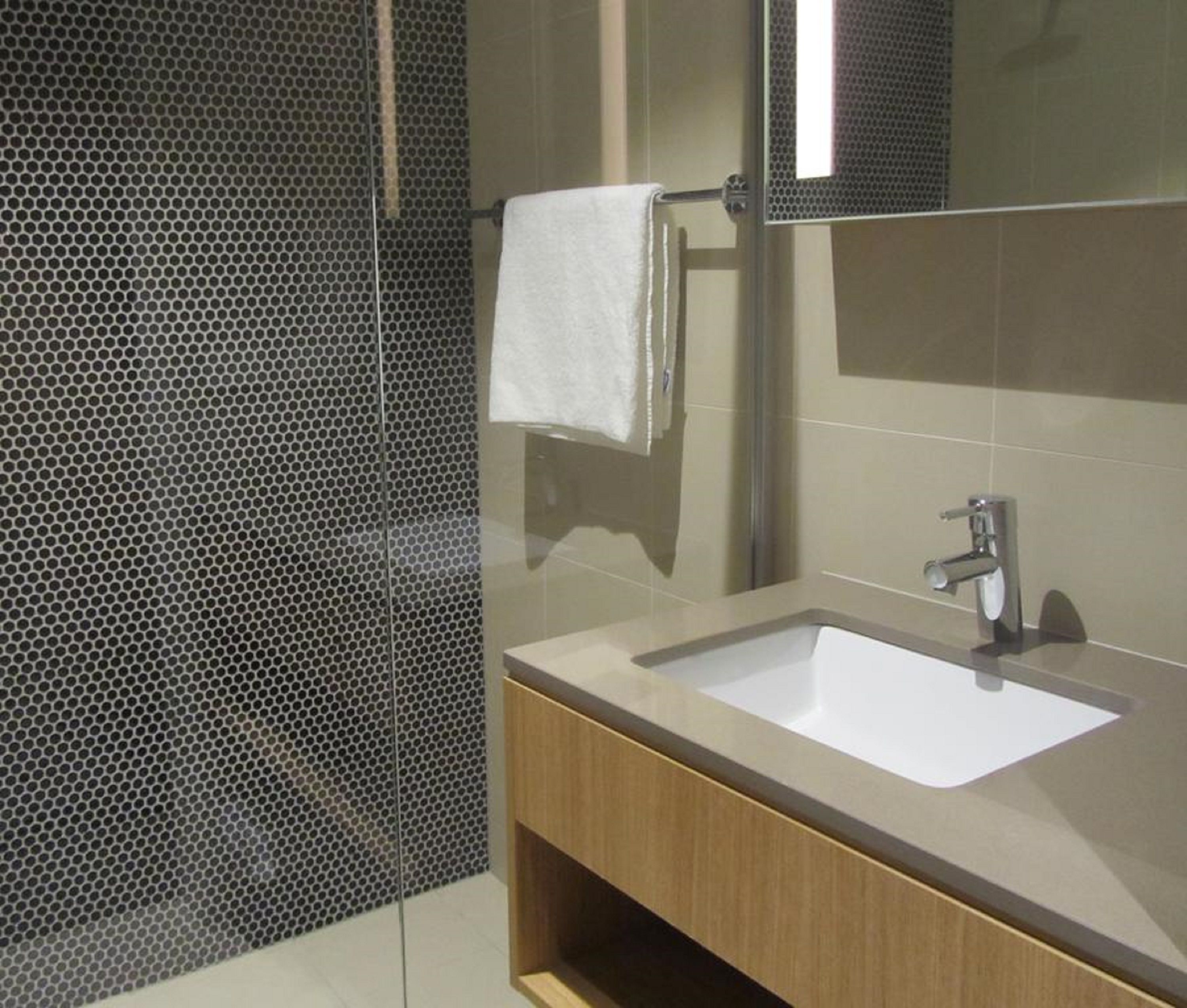 Un baño moderno con un lavamanos grande, un espejo y una zona de ducha con puerta de cristal.