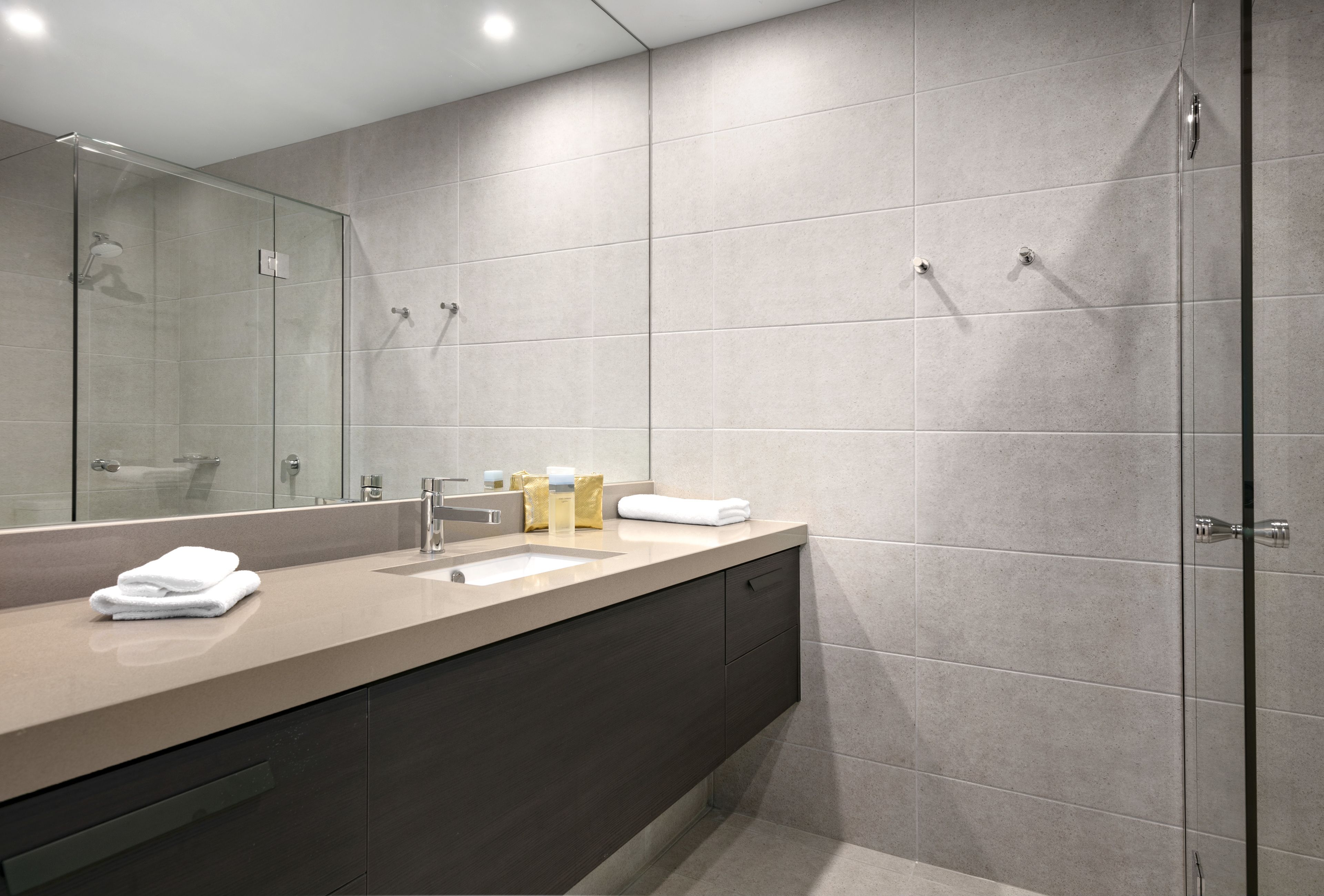 Un baño moderno con un espejo grande, un lavamanos y una zona de ducha.