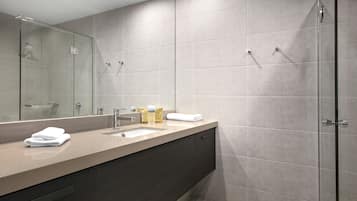 Un baño moderno con un espejo grande, un lavamanos y una zona de ducha.