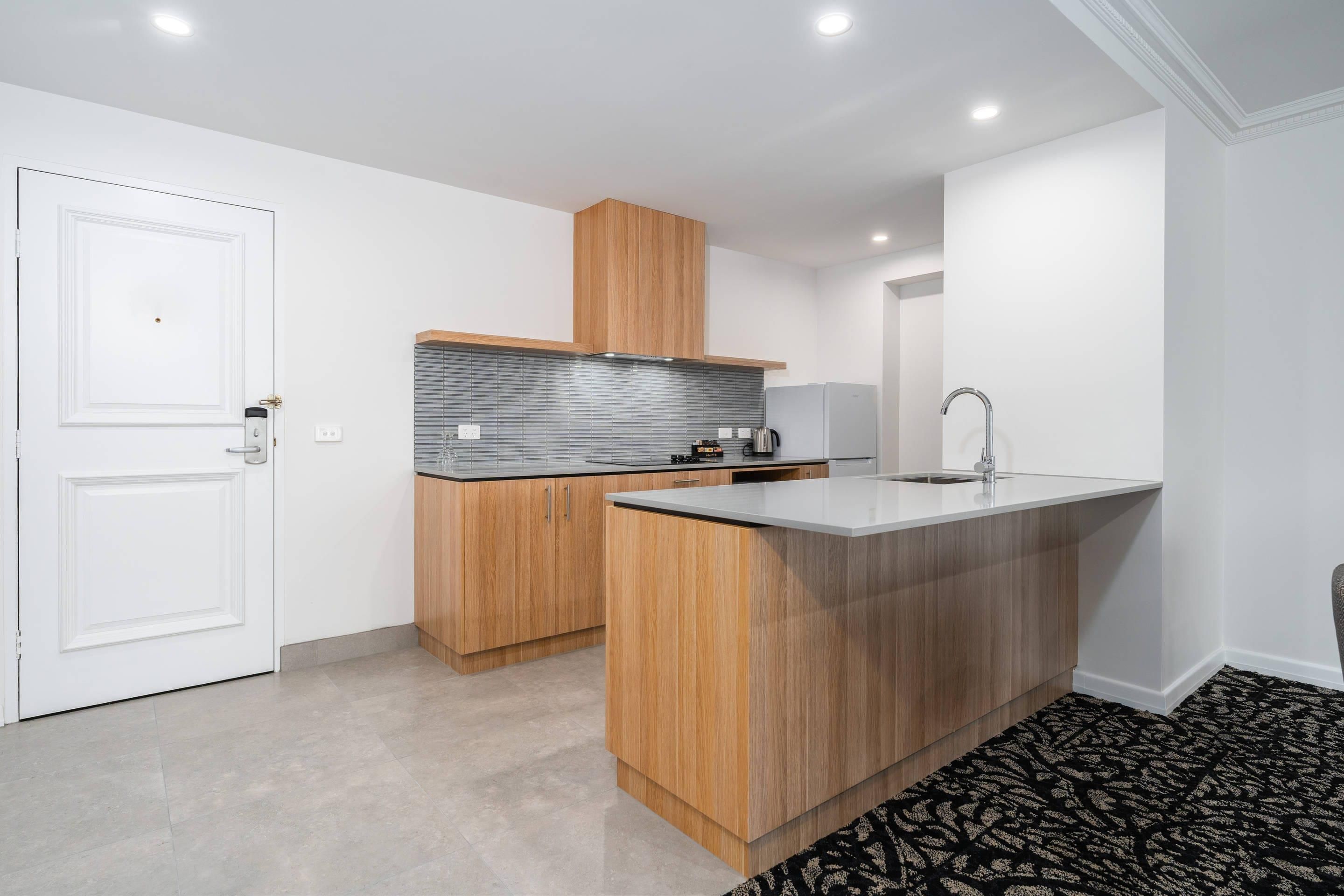 Une cuisine moderne avec des meubles en bois, une hotte en acier inoxydable et un évier encastré.