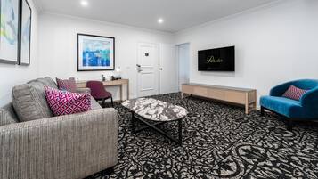 A modern living room with a sofa, a blue armchair, a coffee table, a TV, and a patterned carpet.
