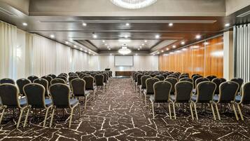A conference room with rows of chairs, a projector screen, and a chandelier.