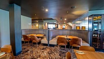Un interior de restaurante moderno con asientos tipo cabina, mesas de madera y una alfombra estampada.