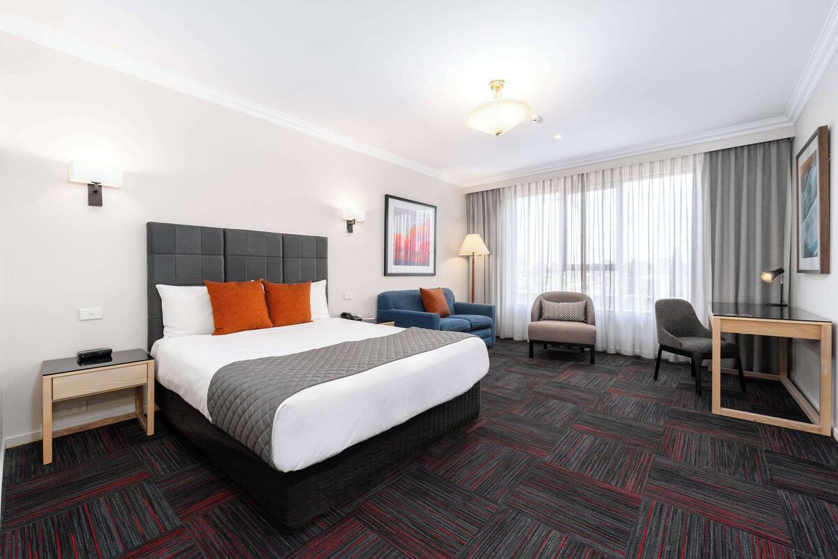 Una habitación de hotel con una cama grande, un escritorio, una silla y un sofá.