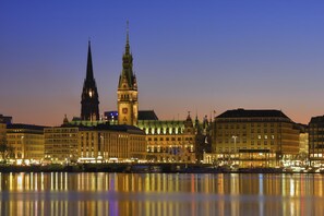 Un paisaje urbano histórico con imponentes torres y un río que refleja los edificios.