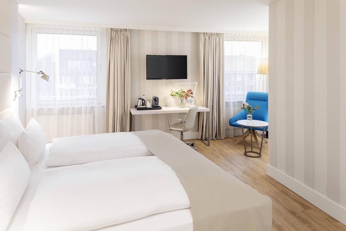 A hotel room with a large bed, a desk with a computer, a TV, and a chair.