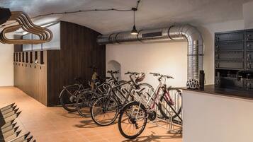 A bicycle storage area with multiple bikes, a wooden cabinet, and a ventilation duct.