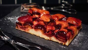 A slice of fruit-topped tart on a slate plate.