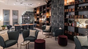 Eine moderne Bibliothek mit einem runden Tisch, mehreren Stühlen und Bücherregalen voller Bücher und Dekoration.